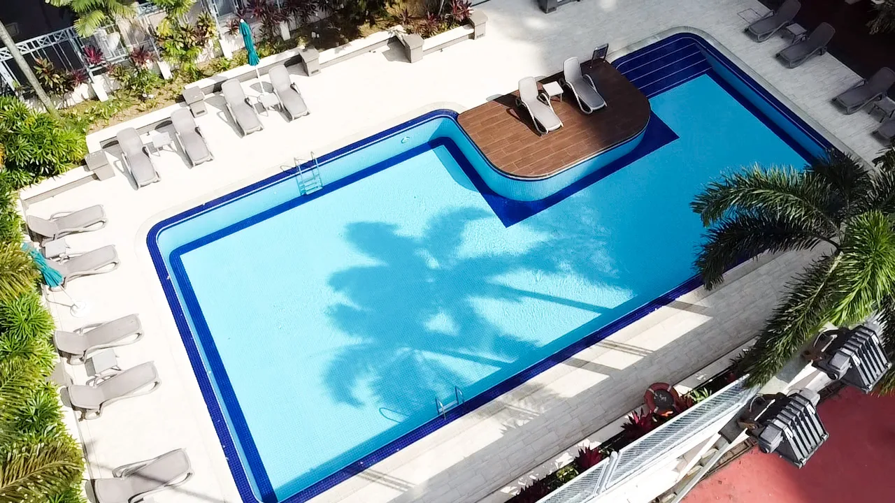 Overhead view of the pool with its timber sun deck, loungers and palm shade